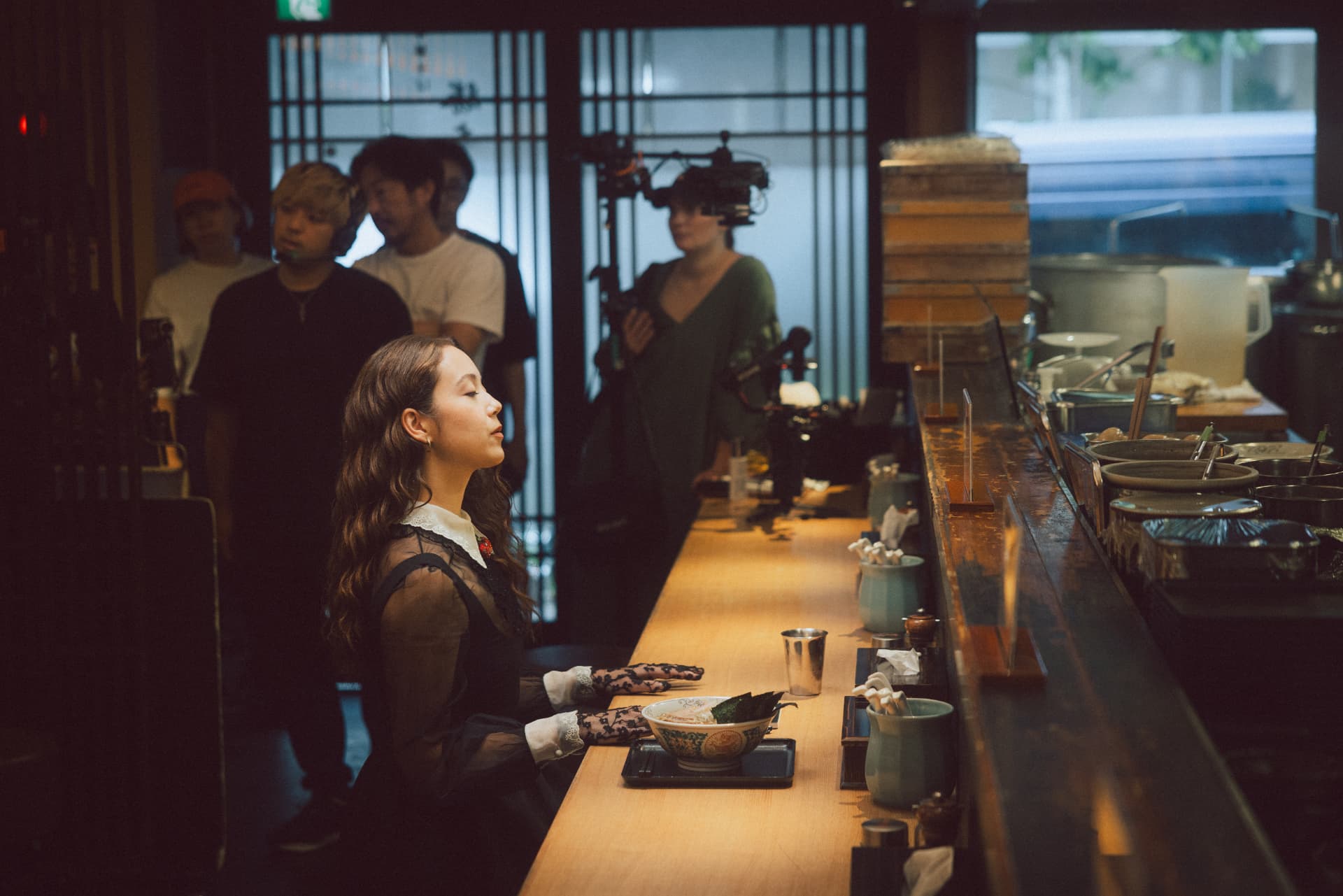 Laufey seated at a restaurant counter during filming
