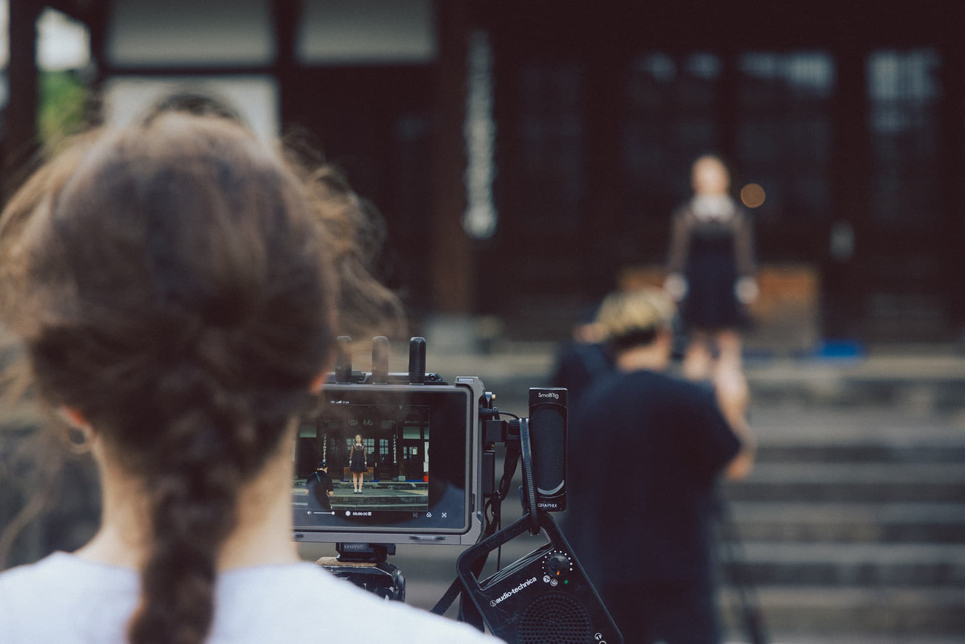 Camera operator filming Laufey in front of a traditional building